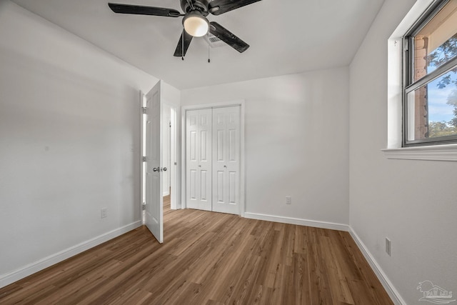 unfurnished bedroom featuring a closet, baseboards, and wood finished floors