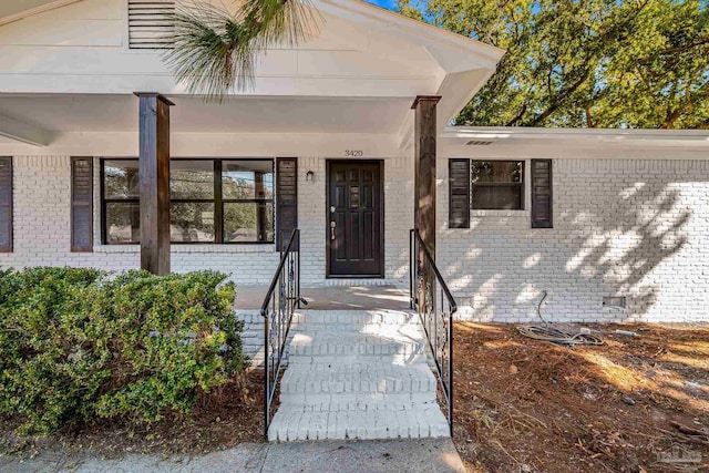 view of exterior entry with covered porch and brick siding