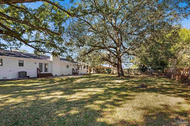 view of yard with entry steps, french doors, a fenced backyard, and central air condition unit