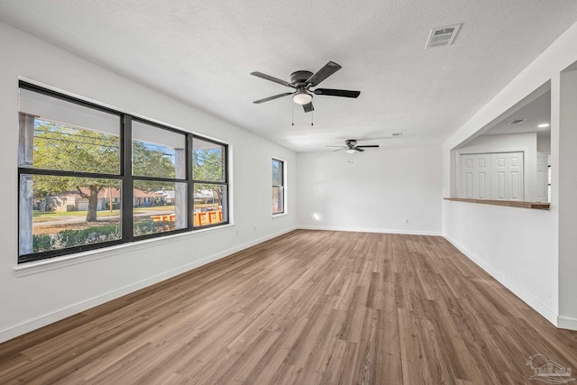 unfurnished room featuring baseboards, a textured ceiling, visible vents, and wood finished floors