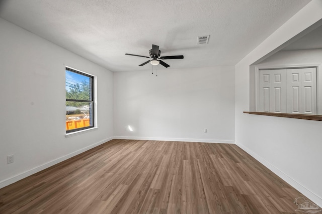 empty room featuring a textured ceiling, baseboards, and wood finished floors