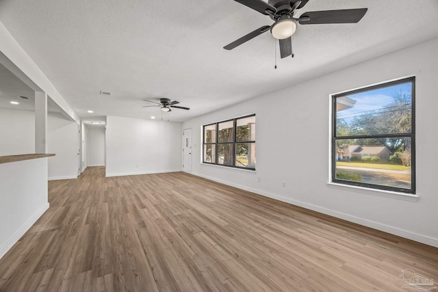 empty room featuring a ceiling fan, a textured ceiling, baseboards, and wood finished floors