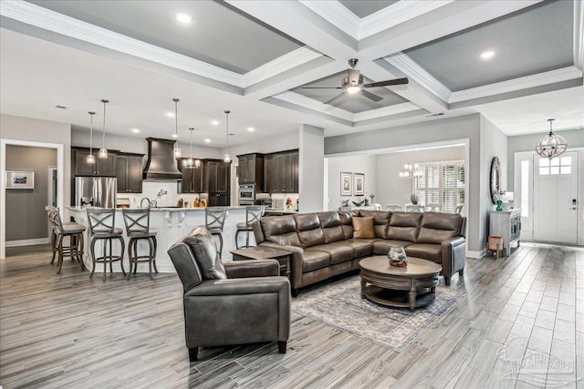 living area featuring light wood finished floors, baseboards, and beamed ceiling