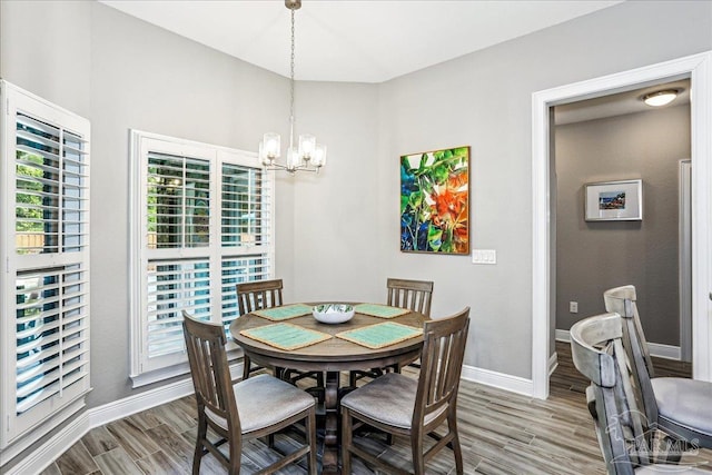 dining space featuring baseboards, a notable chandelier, and wood finished floors