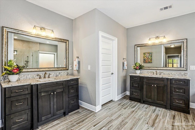 bathroom with baseboards, two vanities, visible vents, and a sink
