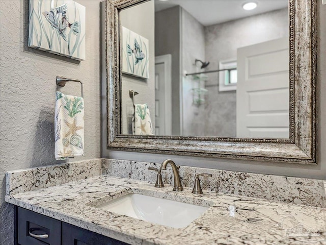 bathroom featuring a shower, vanity, and a textured wall