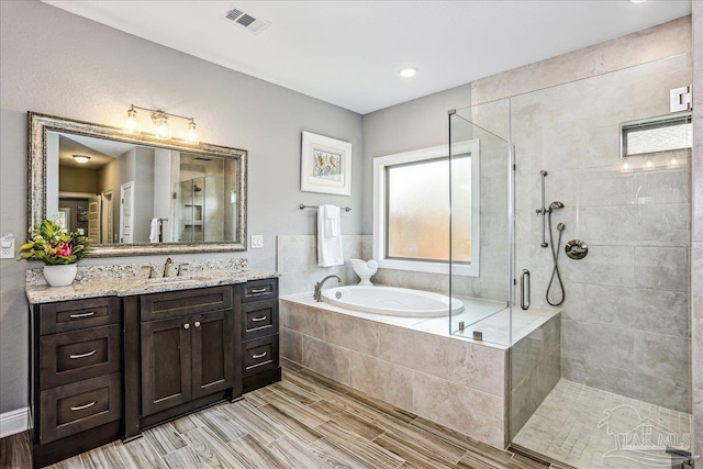 bathroom with a stall shower, wood tiled floor, visible vents, and a bath