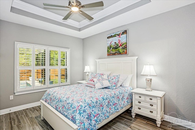 bedroom featuring a tray ceiling, ceiling fan, wood finish floors, and baseboards