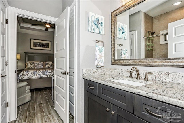 bathroom with walk in shower, vanity, wood finish floors, and ceiling fan