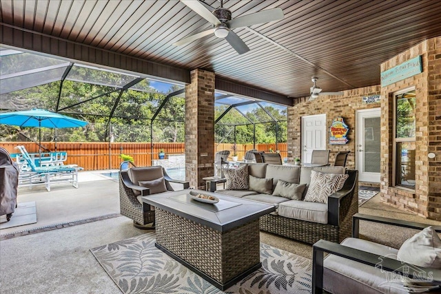 view of patio / terrace featuring an outdoor living space, an outdoor kitchen, fence, ceiling fan, and glass enclosure