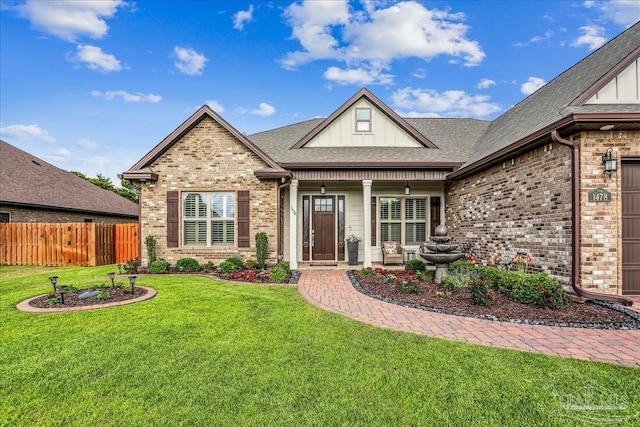 craftsman-style house featuring a front lawn, a shingled roof, brick siding, and fence
