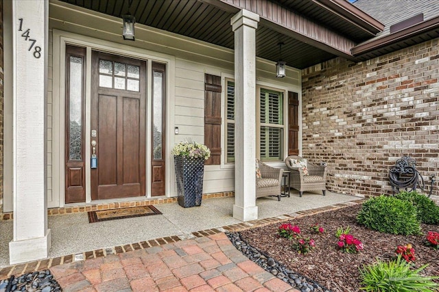 property entrance featuring a porch and brick siding