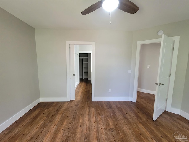 unfurnished bedroom featuring a closet, a spacious closet, wood-type flooring, and ceiling fan