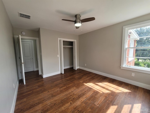 unfurnished bedroom with multiple windows, dark hardwood / wood-style floors, ceiling fan, and a closet