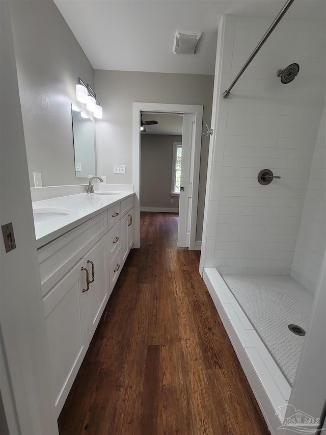 bathroom with tiled shower, dual vanity, and hardwood / wood-style floors