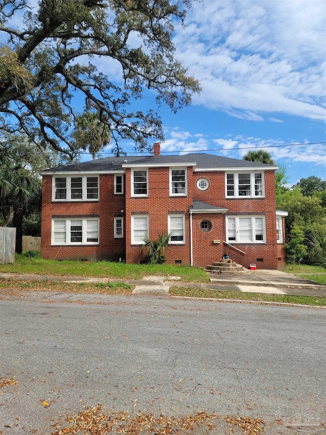 view of front facade featuring crawl space, brick siding, and a chimney