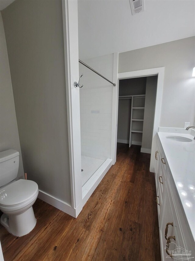 bathroom with vanity, toilet, a tile shower, and hardwood / wood-style flooring