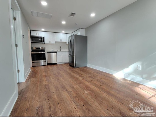 kitchen featuring white cabinetry, stainless steel appliances, sink, and light wood-type flooring