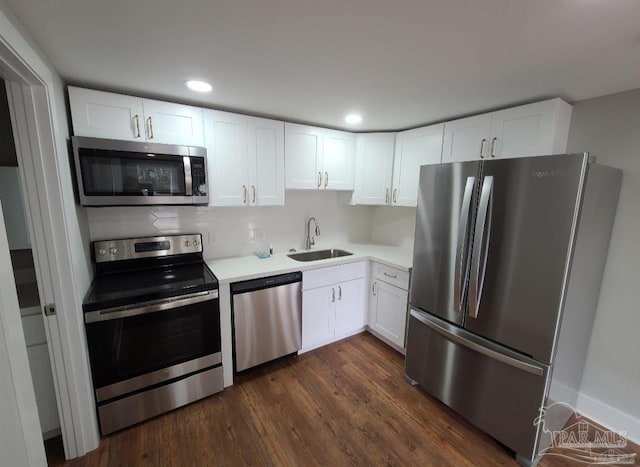 kitchen with white cabinetry, stainless steel appliances, sink, backsplash, and dark wood-type flooring