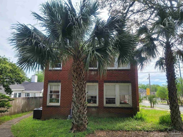 view of side of property with brick siding, cooling unit, and fence