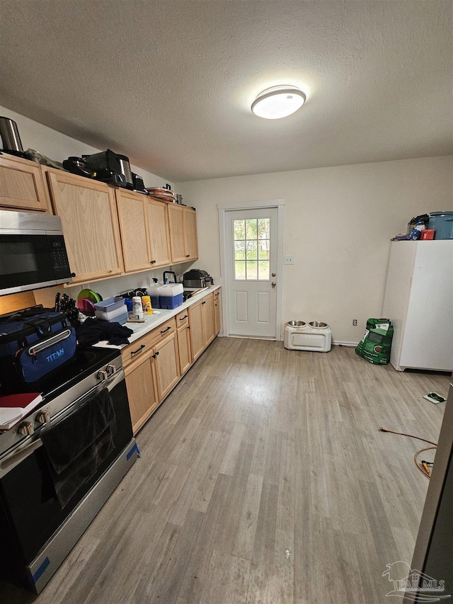 kitchen with appliances with stainless steel finishes, light brown cabinets, a textured ceiling, and light hardwood / wood-style floors