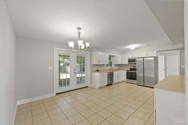 kitchen with white cabinetry, french doors, hanging light fixtures, stainless steel appliances, and light tile patterned floors