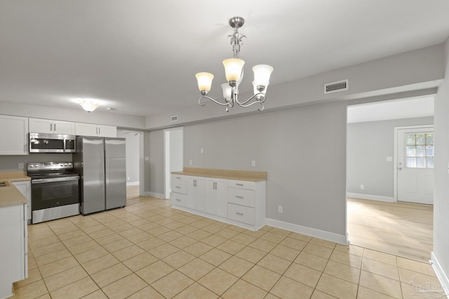 kitchen featuring white cabinets, a notable chandelier, pendant lighting, light tile patterned floors, and appliances with stainless steel finishes