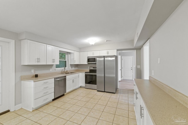 kitchen with light tile patterned floors, white cabinetry, sink, and appliances with stainless steel finishes