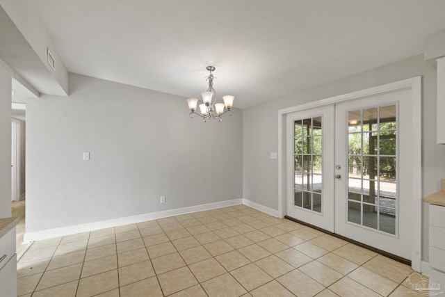 tiled empty room with an inviting chandelier and french doors