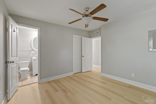 unfurnished bedroom featuring ceiling fan, light hardwood / wood-style floors, electric panel, and connected bathroom