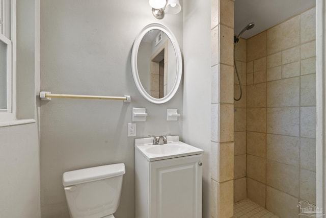 bathroom with vanity, toilet, and a tile shower