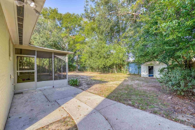 view of yard with a sunroom, a storage unit, and a patio area