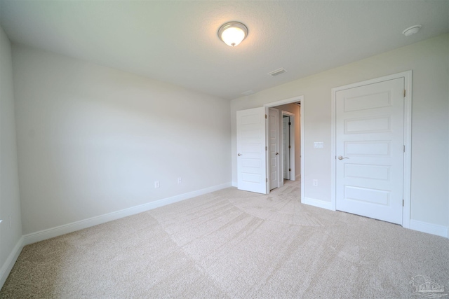 unfurnished bedroom with light colored carpet and a closet