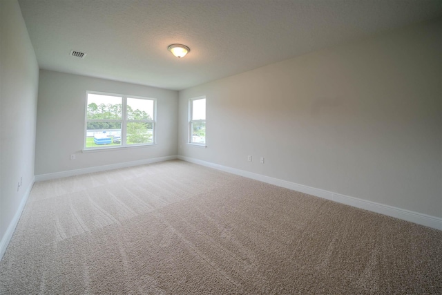 carpeted empty room featuring a textured ceiling