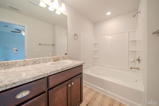 bathroom featuring hardwood / wood-style flooring, vanity, and bathing tub / shower combination