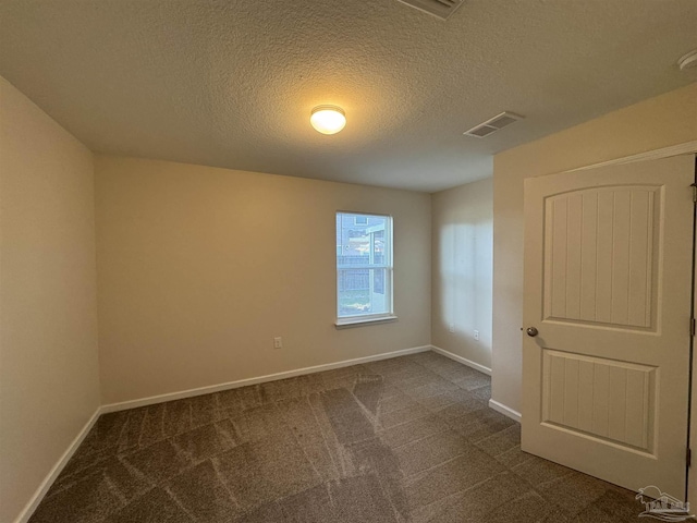 unfurnished room featuring baseboards, a textured ceiling, and dark carpet