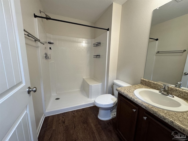 bathroom with toilet, wood finished floors, a shower, and vanity