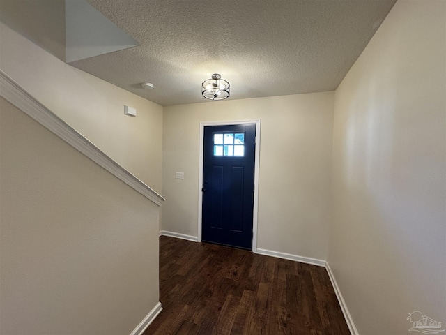foyer entrance featuring baseboards, a textured ceiling, and dark wood-style floors