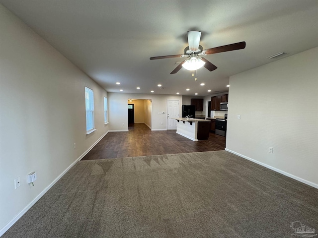 unfurnished living room with dark colored carpet, a ceiling fan, baseboards, recessed lighting, and visible vents