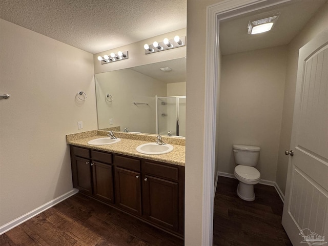 bathroom with a sink, double vanity, a shower stall, and wood finished floors