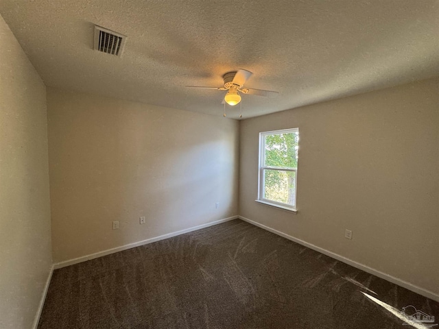 unfurnished room with ceiling fan, a textured ceiling, dark colored carpet, baseboards, and visible vents
