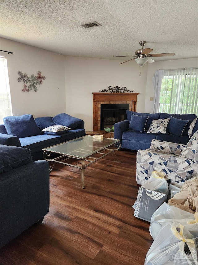 living room with ceiling fan, a textured ceiling, and dark wood-type flooring