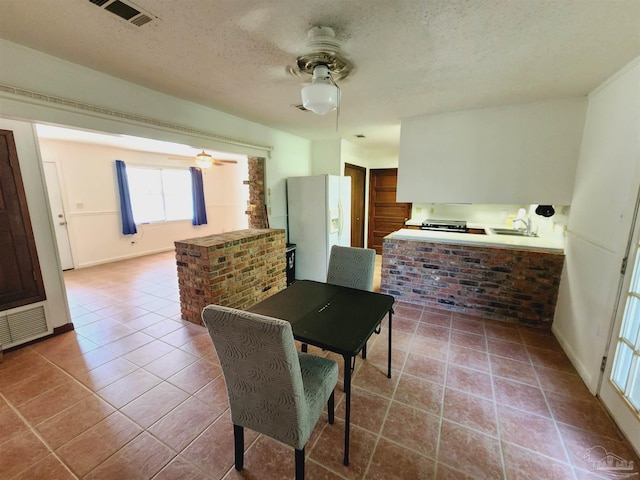 tiled dining area featuring sink, a textured ceiling, and ceiling fan