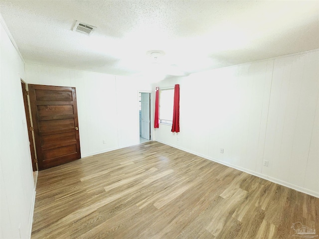 spare room with a textured ceiling and light wood-type flooring