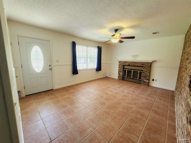 unfurnished living room featuring a brick fireplace, a textured ceiling, light tile patterned floors, and ceiling fan