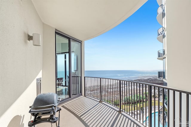 balcony with a water view, a beach view, and grilling area