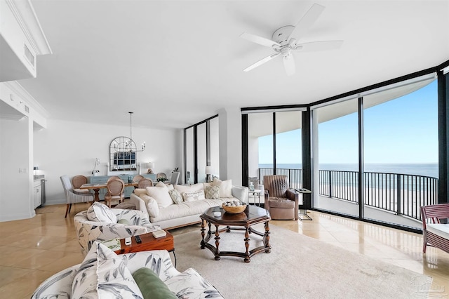 living area featuring light tile patterned floors, ceiling fan with notable chandelier, a water view, a wall of windows, and baseboards