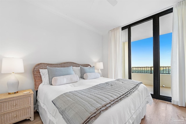 bedroom featuring a wall of windows, access to outside, and light wood-style floors