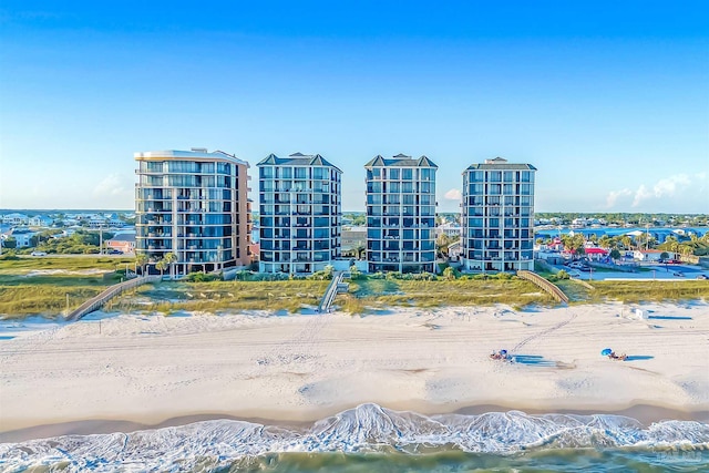 drone / aerial view with a water view, a view of the beach, and a view of city