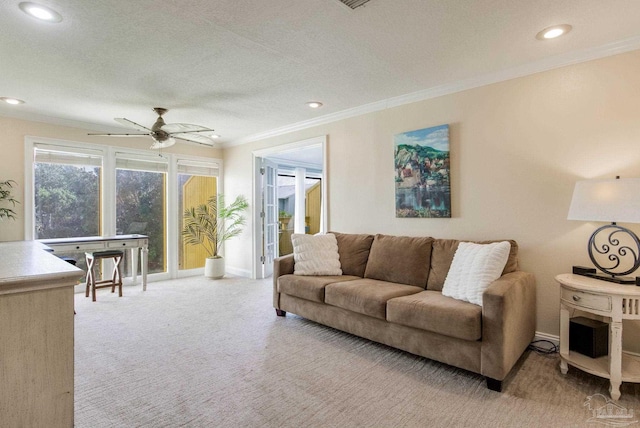 living room featuring ceiling fan, a textured ceiling, light carpet, and ornamental molding